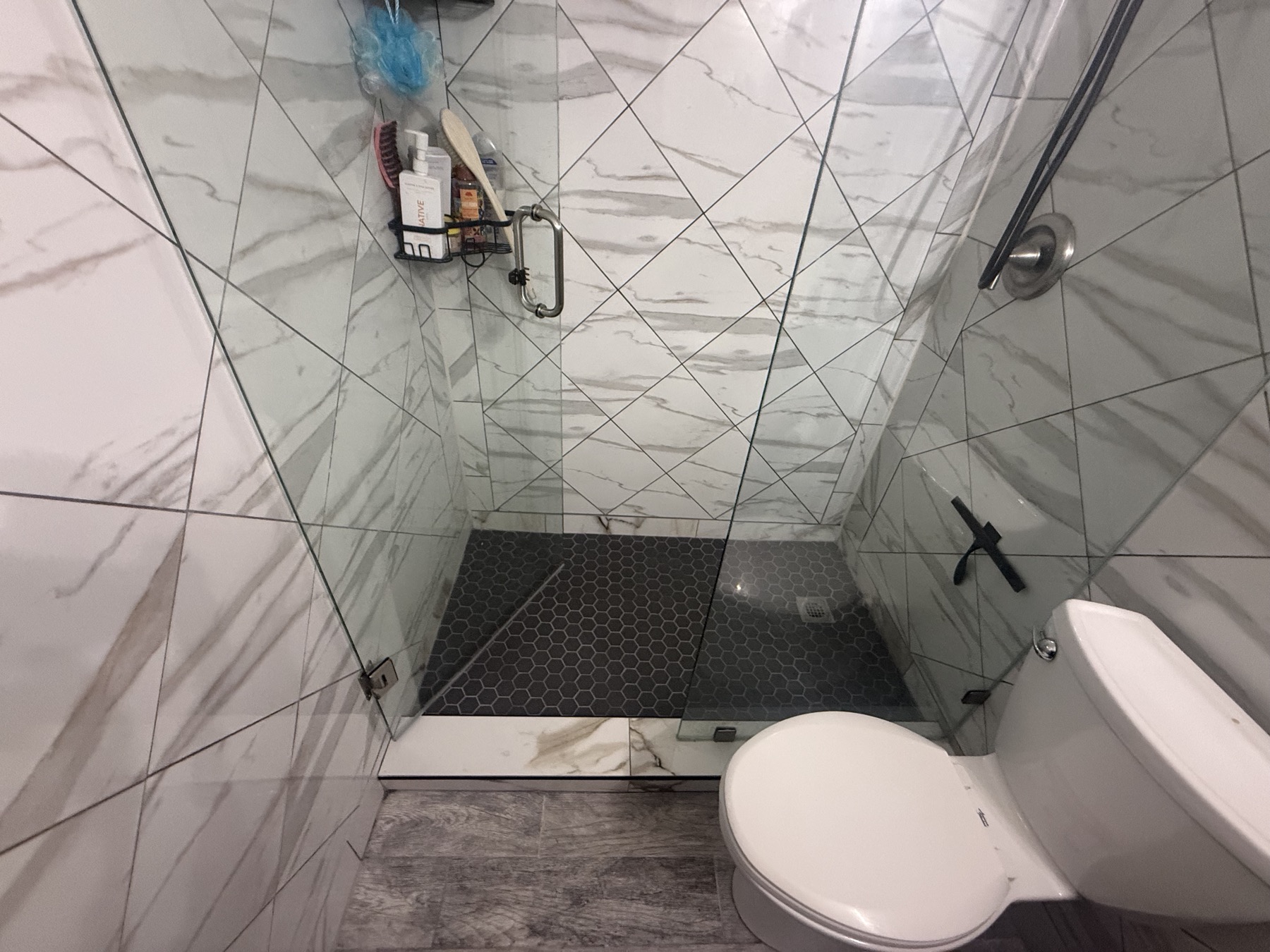 Small bathroom with marble tile and black hex shower floor