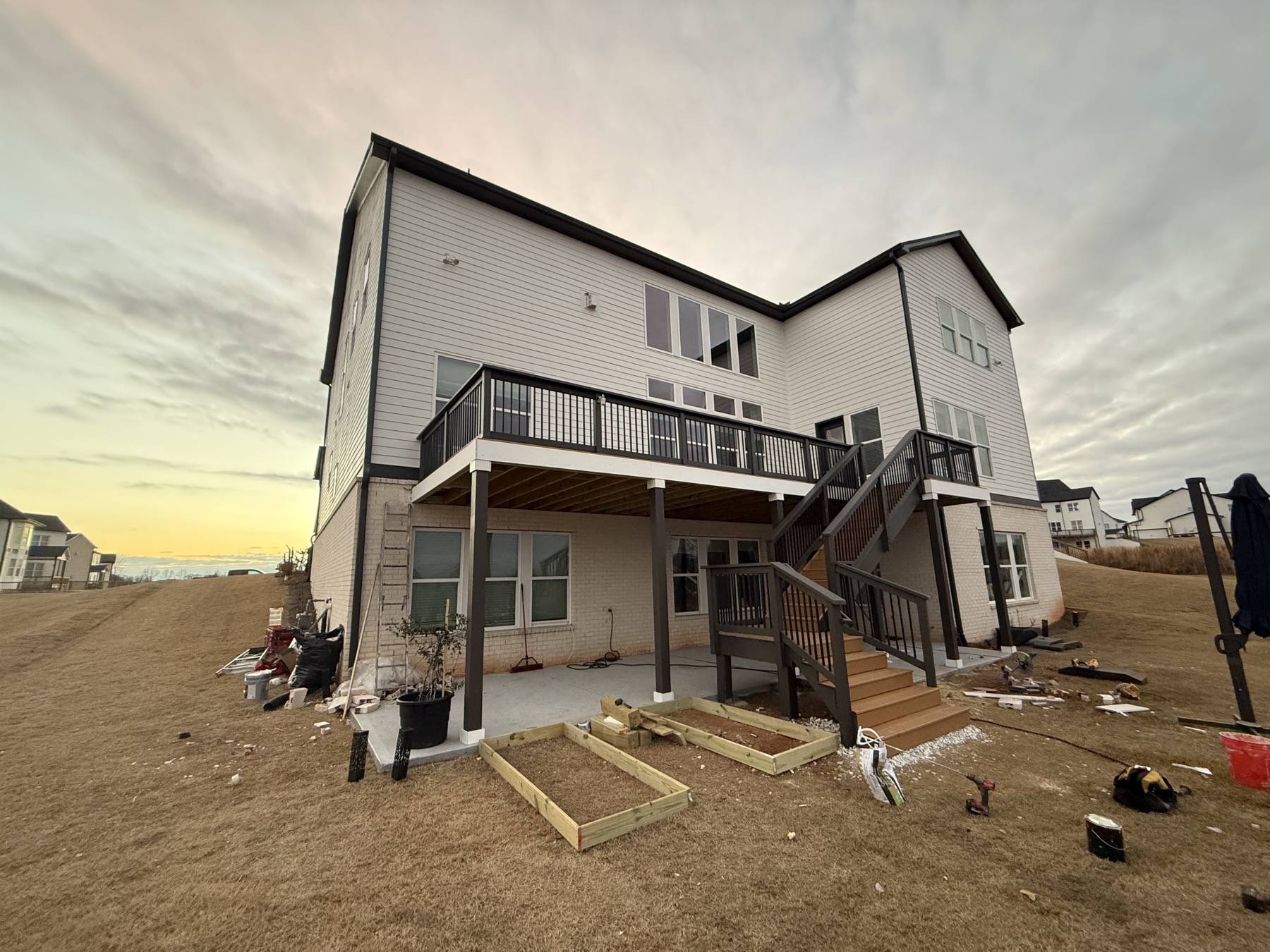 Finished exterior with white-wrapped rim joist, new patio and garden beds below