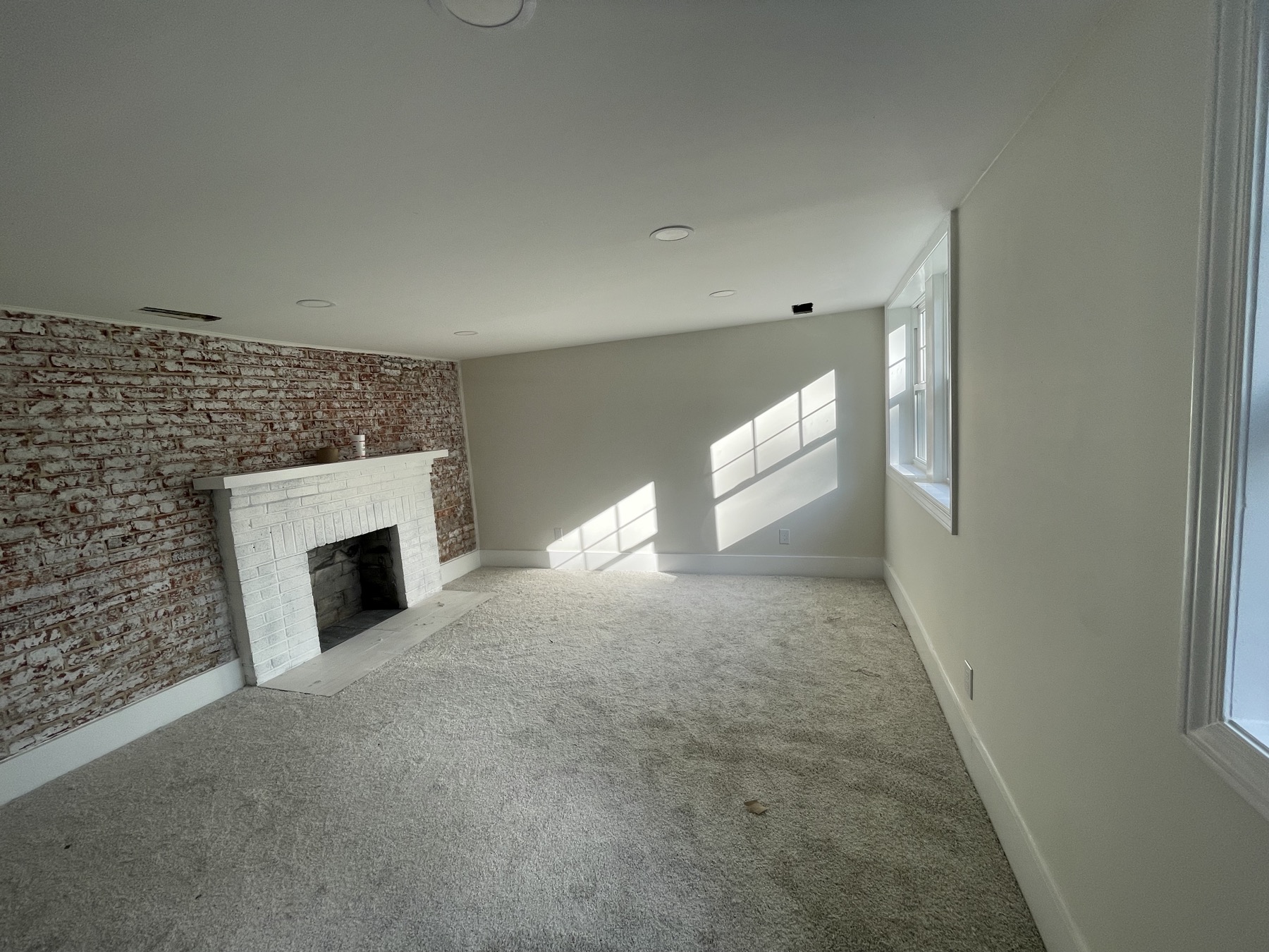 Finished living room with whitewashed brick fireplace