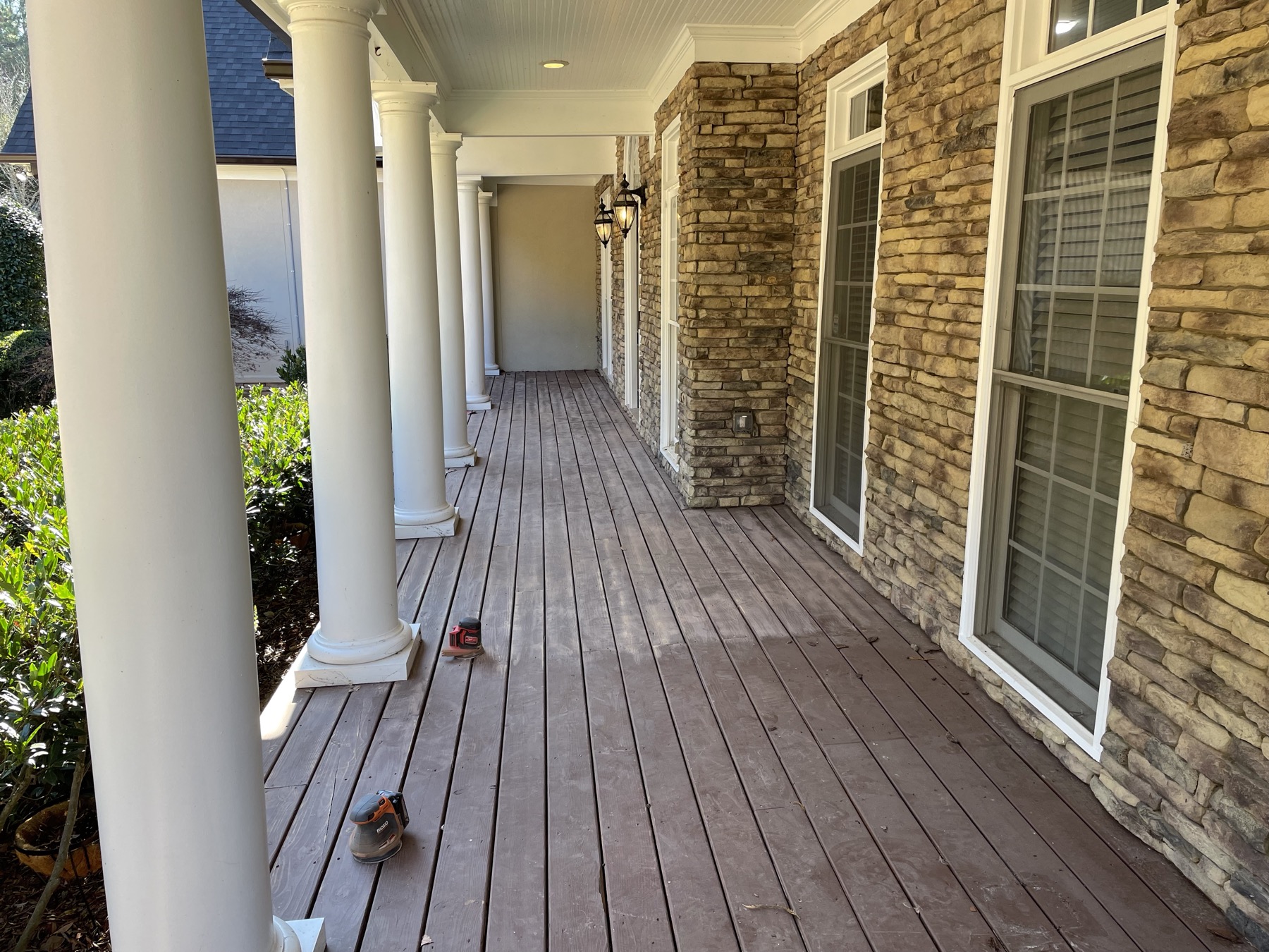 Stained covered porch with white columns and stone accents